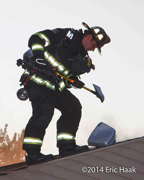fireman on the roof of a house with an ax