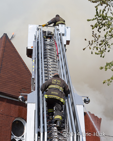 firemen climb tower ladder at fire scene