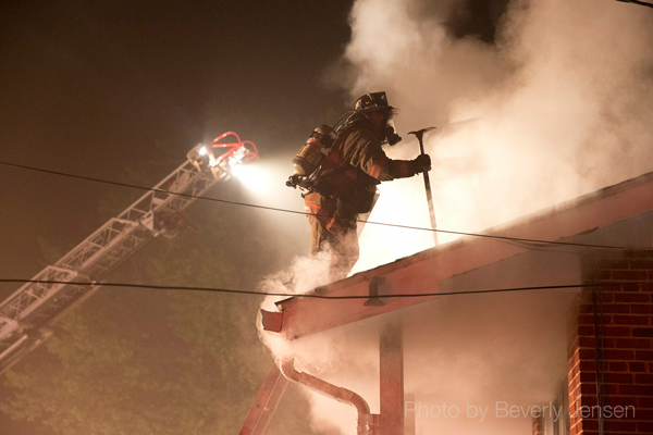 fireman on roof at night surrounded by smoke