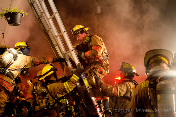 firemen climb ground ladder at night fire scene 
