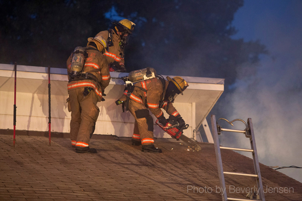 firemen vent house roof during fire
