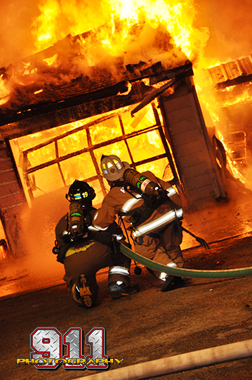 firemen battle a house fyllu engulfed in flames at night