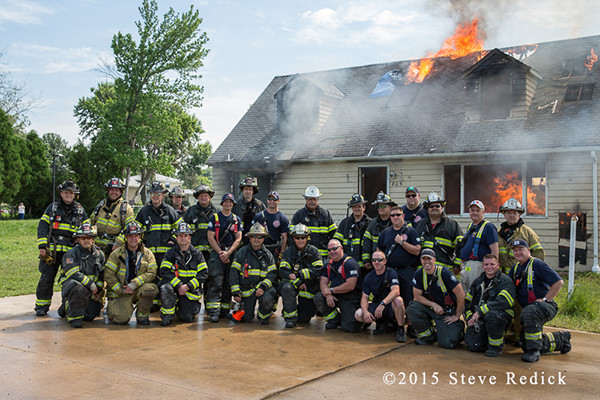 firemen pose with burning house