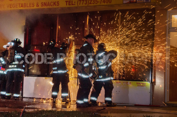 firemen cutting a metal gate at night
