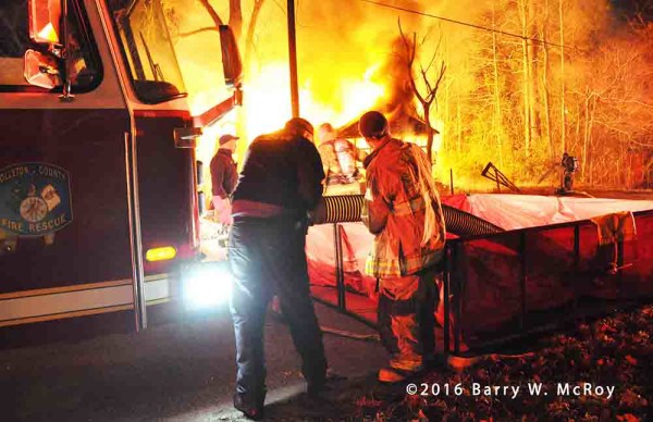 firefighters draft from a portable tank at a rural house fire