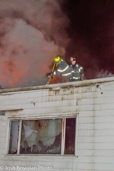 firefighters on roof of house on fire