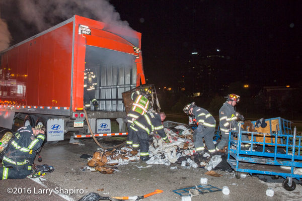 firemen overhaul truck contents after fire