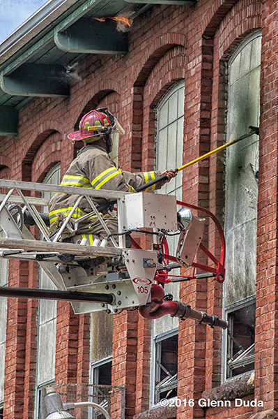 firefighter on aerial ladder tip at fire scene