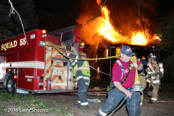 firefighter pulls hose at a fire scene