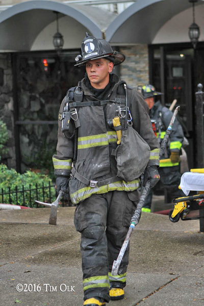 firefighter in PPE with tools after a fire