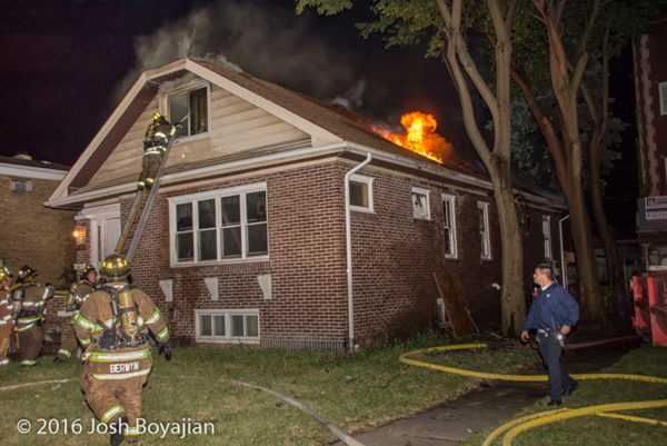 firefighters battle fire through the roof of a house on fire