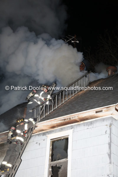 firefighter on ladder carrying a roof ladder