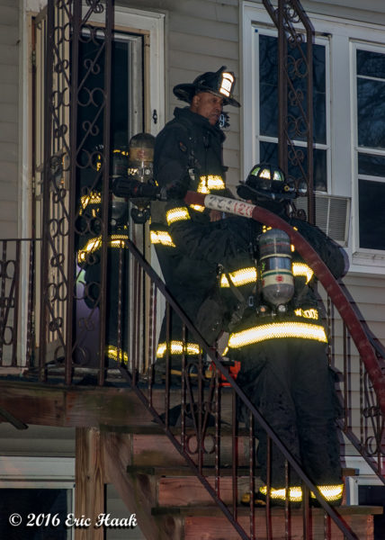 firefighters with hose at front door