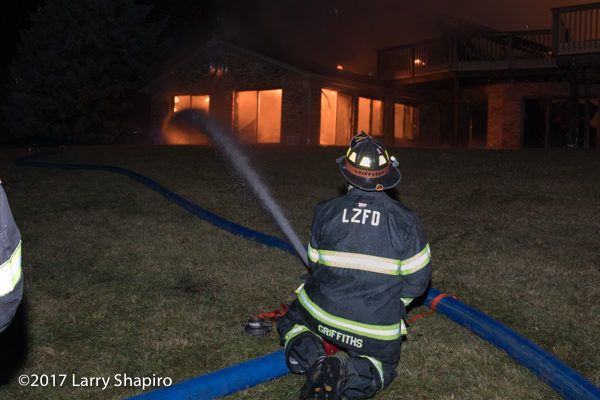 Firefighter with ground monitor fighting house fire