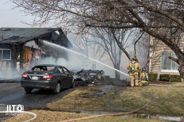 firefighters spray water on house fire