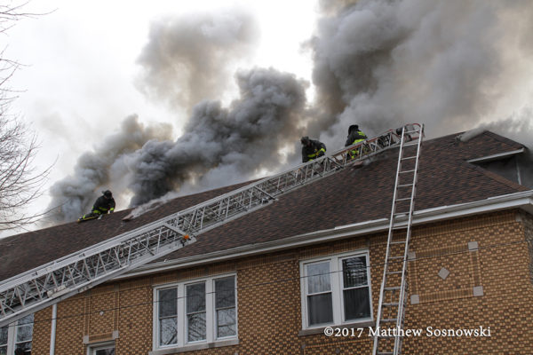 firefighters on peak roof to vent fire with heavy smoke