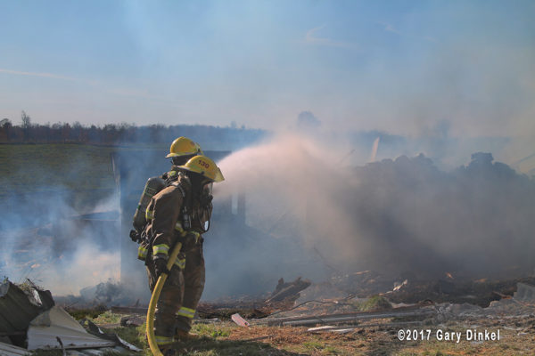 firefighters with hose line at barn fire