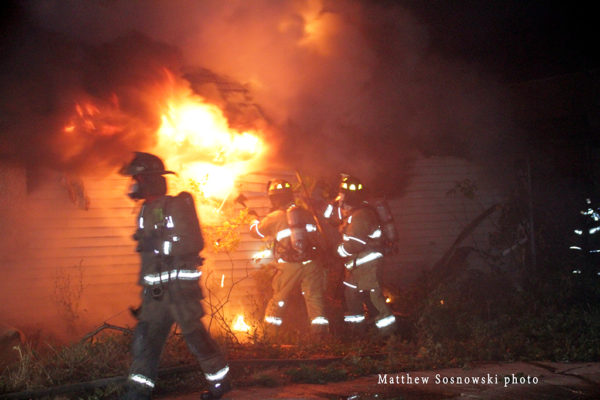firefighters battle house fire at night
