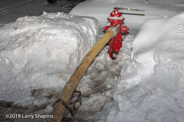 fire hydrant with hose attached dug out from snow