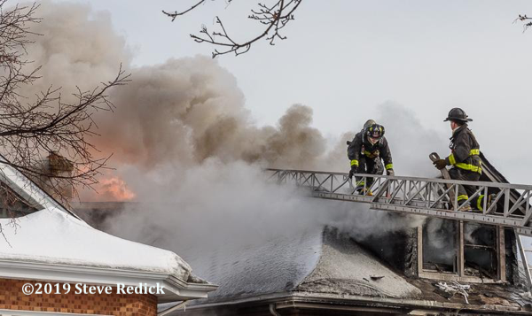 Firefighters on aerial ladder battle a Chicago bungalow on fire