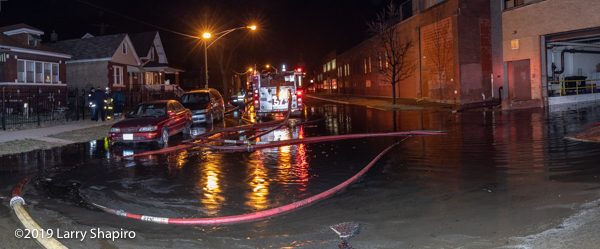 water floods the street around fire engine at massive fire scene