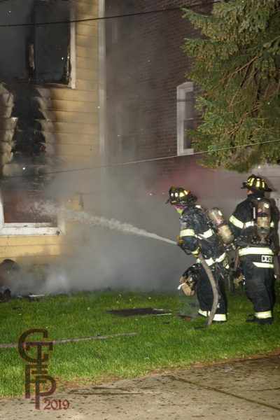 Firefighters with hose line at night fire scene