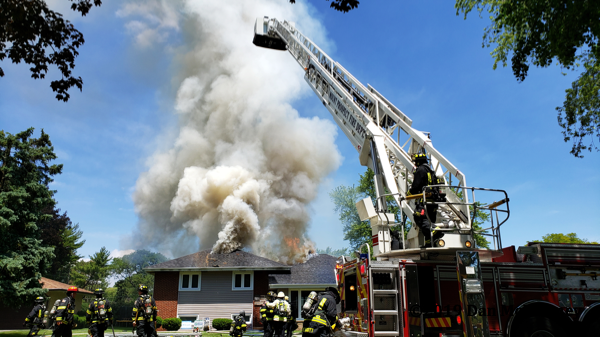 flames and smoke through roof of house on fire