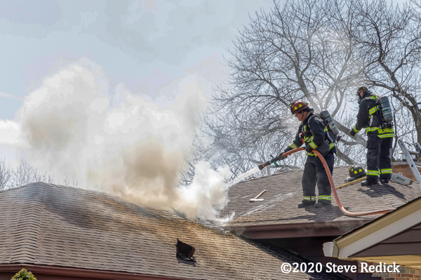 Firefighter on roof extinguishes attic fire